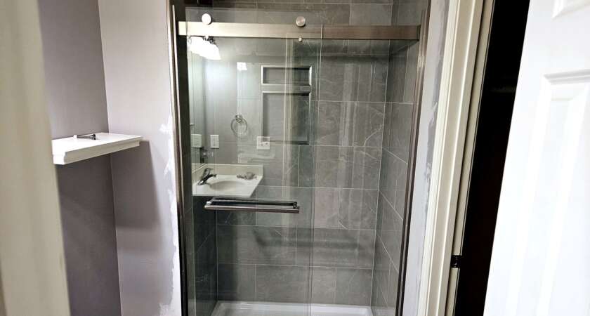 Completed walk-in shower with glass door and modern tile work by Bathroom Bidders in Kansas City