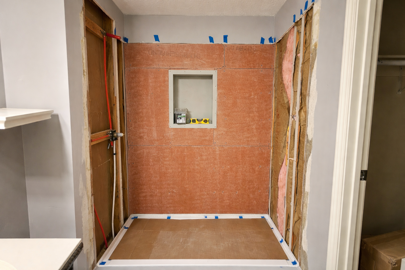 shower mid-construction with orange Schluter Kerdi waterproofing membrane covering the walls