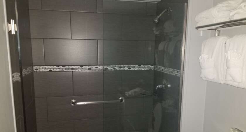 Dark grey tile shower with a mosaic accent band in a Kansas City home after a Bathroom Bidders grout cleaning and sealing