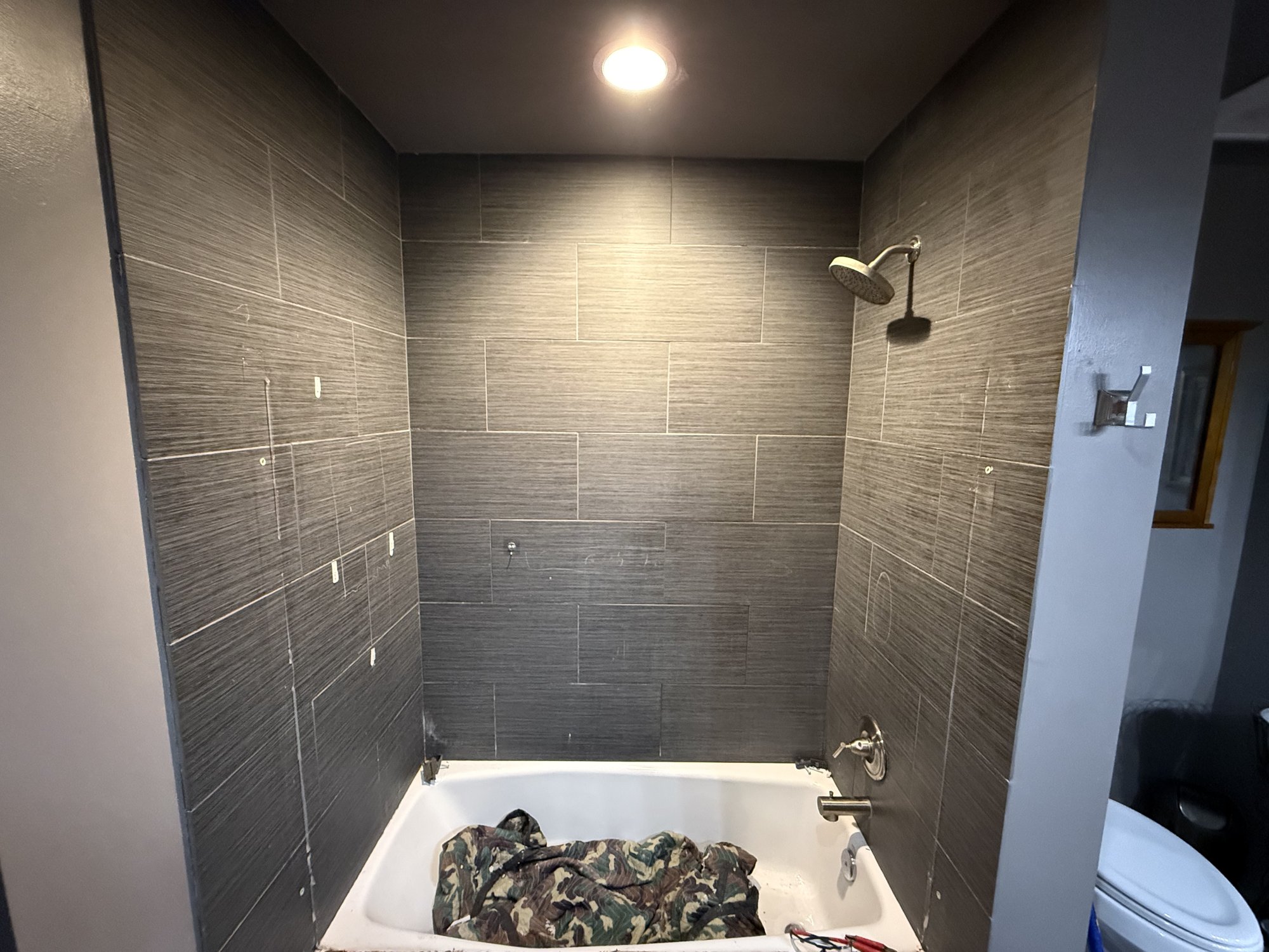 Before: tub and dark gray tile surround in a Kansas City master bathroom